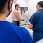 Paciente realiza teste cardiológico enquanto profissionais de saúde monitoram o procedimento em uma clínica.