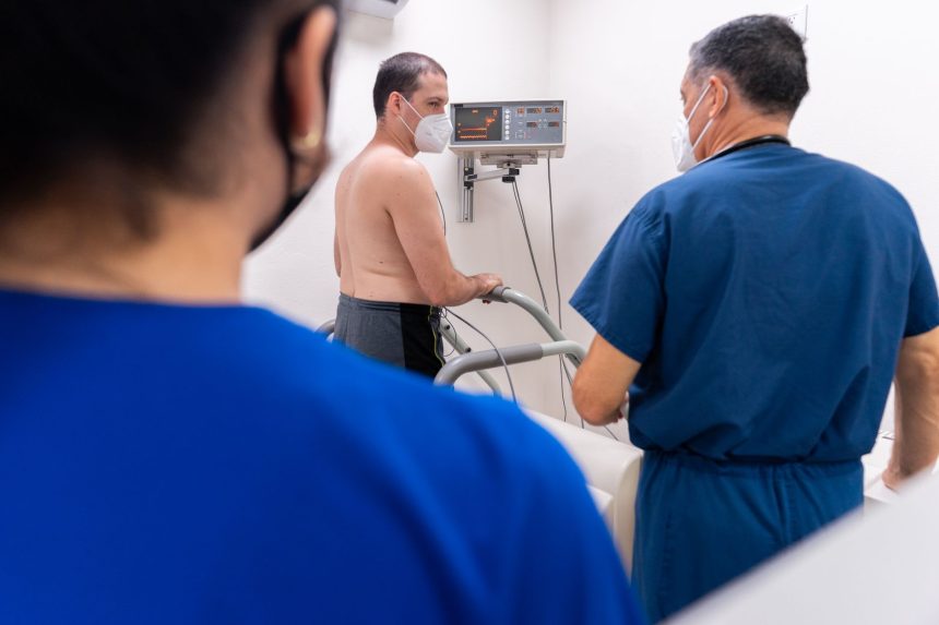 Paciente realiza teste cardiológico enquanto profissionais de saúde monitoram o procedimento em uma clínica.