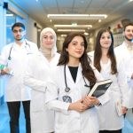 Grupo de estudantes de Medicina usando jalecos em um corredor universitário.
