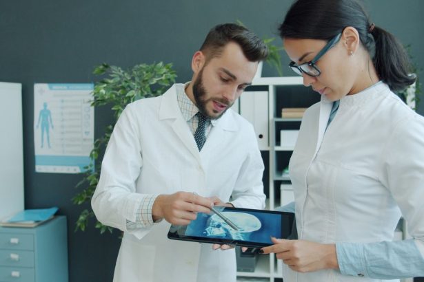 Dois médicos analisam a radiografia de um paciente em um tablet, em um consultório.