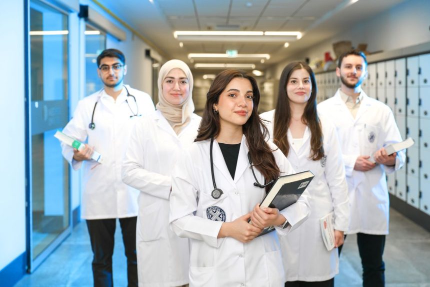 Grupo de estudantes de Medicina usando jalecos em um corredor universitário.