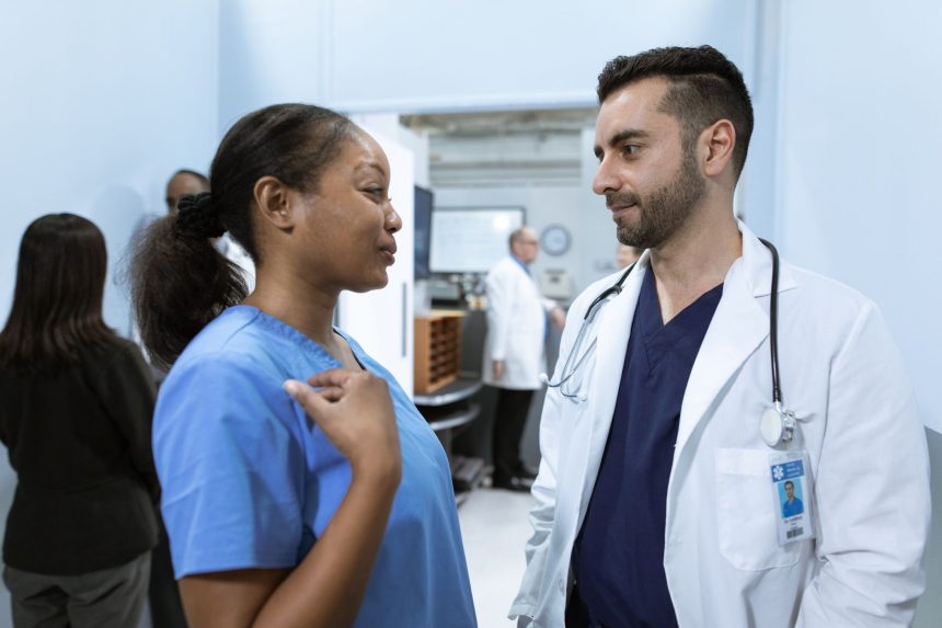 Profissionais de saúde conversam em um corredor de hospital sobre o atendimento a pacientes.