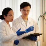 Pesquisadores usando equipamentos de proteção analisam dados em um laboratório.