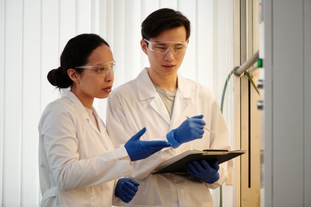Pesquisadores usando equipamentos de proteção analisam dados em um laboratório.